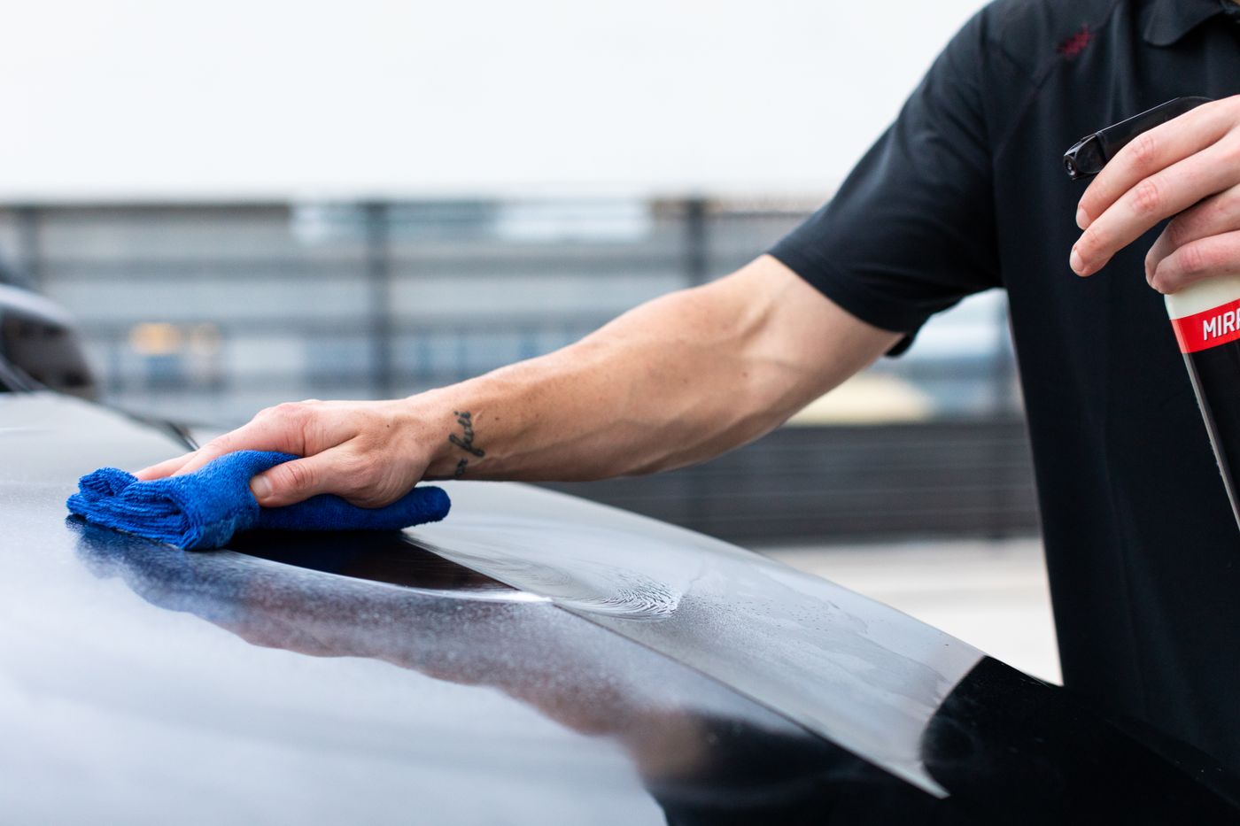 Close-up of a professional preparing a vehicle, wiping the bodywork with a blue cloth